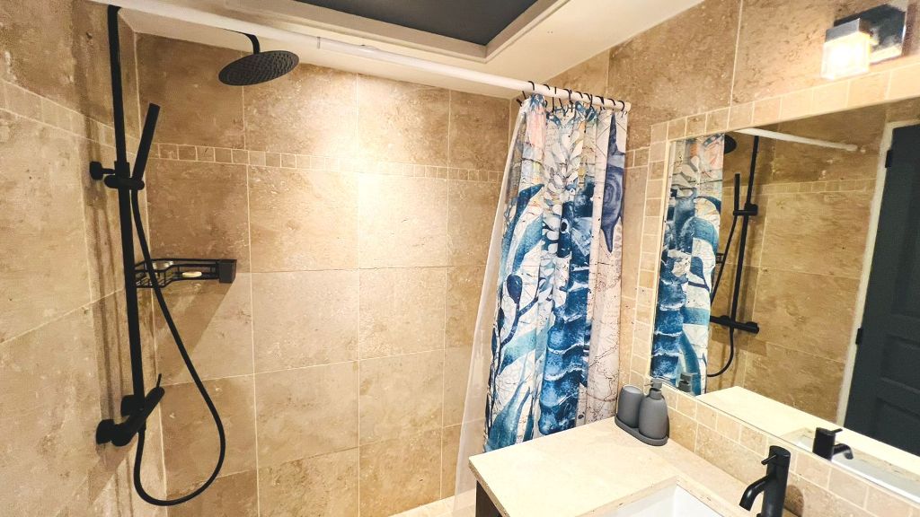 Bathroom with travertine walls and rain shower